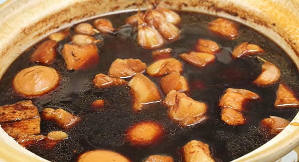 Delicious braised pork belly in soy sauce with hard-boiled eggs and fried tofu in a clay pot.