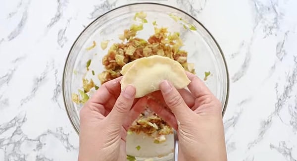 Dumplings being sealed with water.