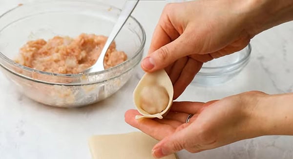 This image shows the wontons being wrapped in a triangle shape.