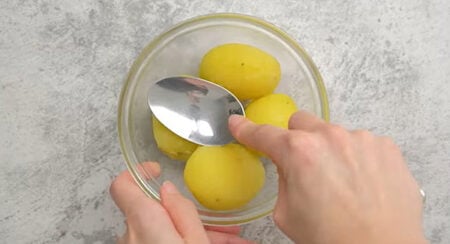 Smashing boiled potatoes with the back of a spoon to make samosas filling. 