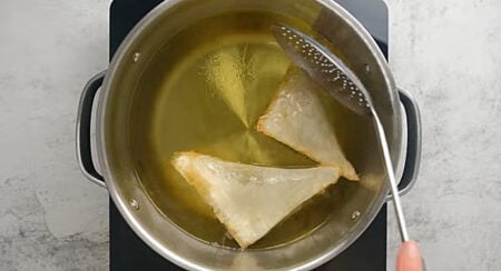 Frying samosas in a pot with hot oil. 