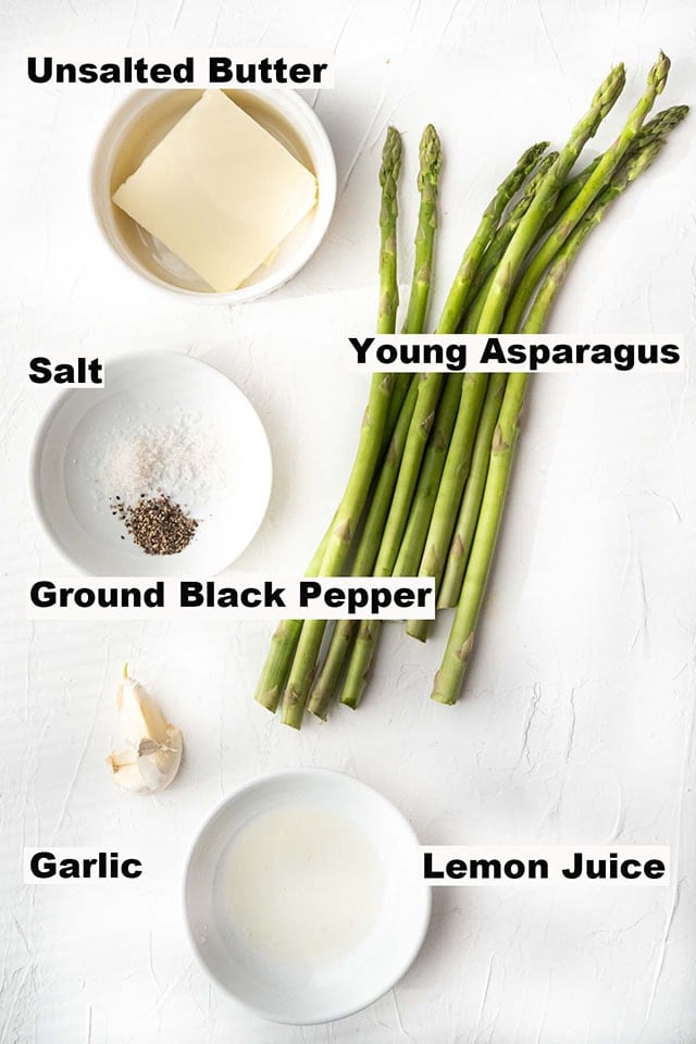 Ingredients for sauteed asparagus such as unsalted butter, young asparagus, salt, ground black pepper, garlic and lemon juice.