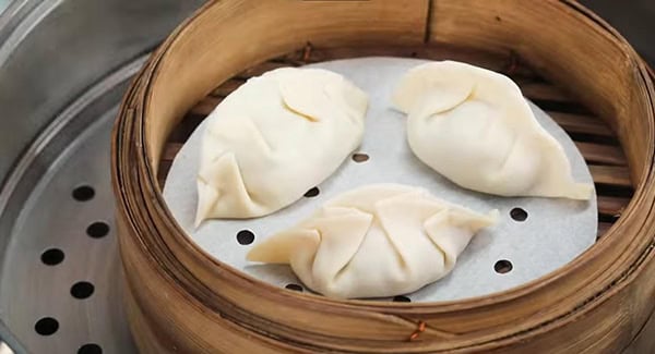 Steaming dumplings in a bamboo steamer. 