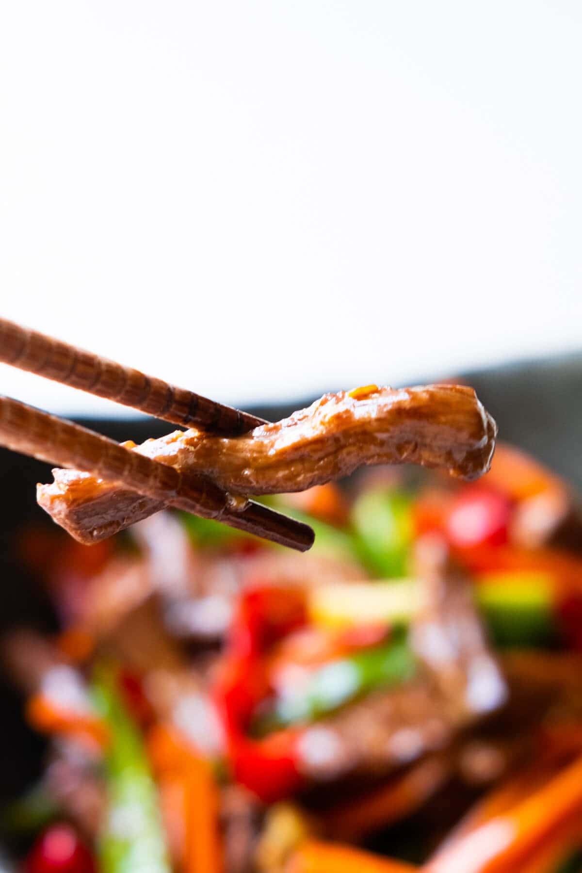 A pair of chopsticks picking up shredded beef. 