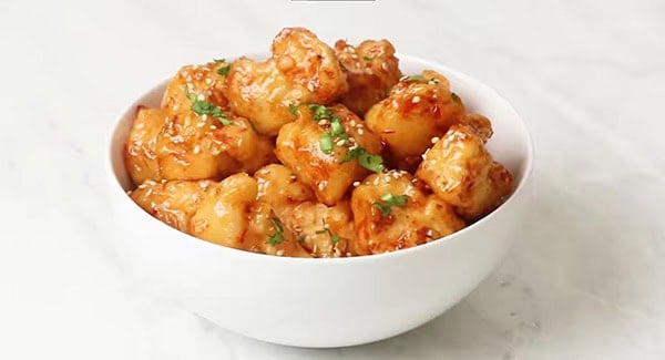 Sweet Chili Chicken garnished with sesame seeds and cilantro leaves. 