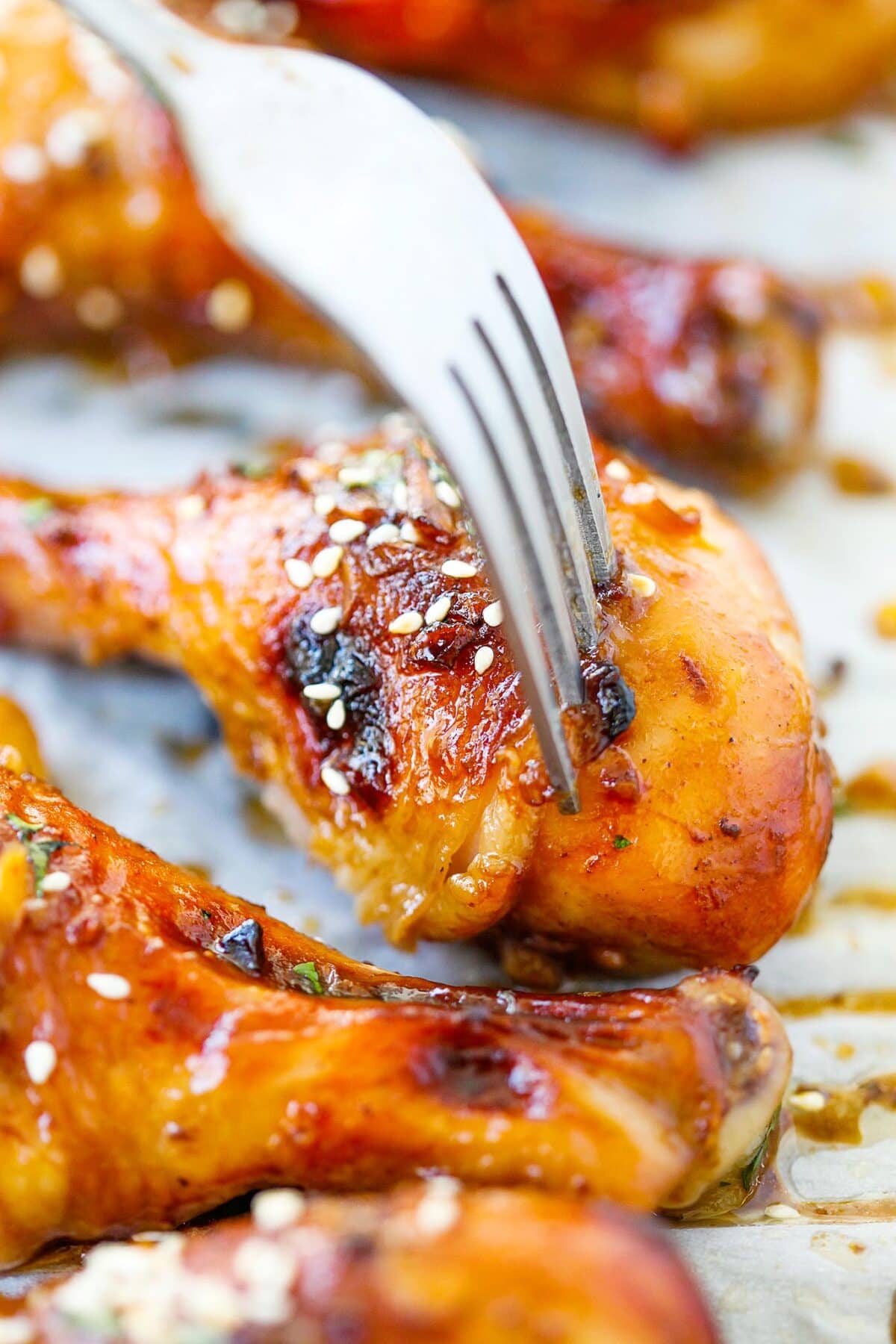 Hoisin-infused baked chicken drumsticks with golden-brown glaze on a baking sheet. 