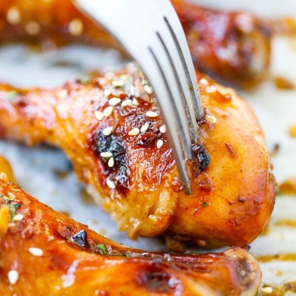 Hoisin-infused baked chicken drumsticks with golden-brown glaze on a baking sheet.