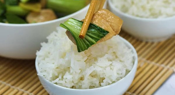 Bok choy and chicken served with a bowl of white rice. 