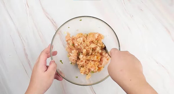 Chicken patties ingredients in a bowl being mixed with spoon. 