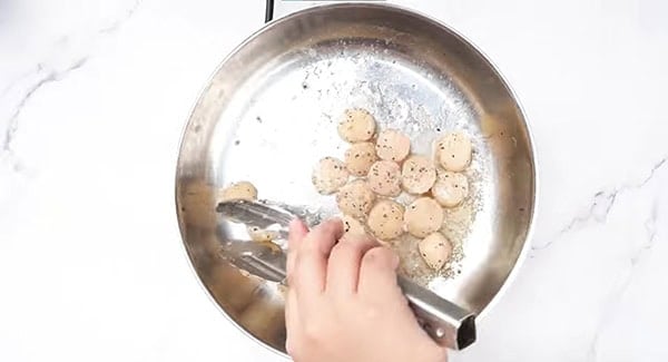 Scallops seasoned with salt and pepper in a pan. 