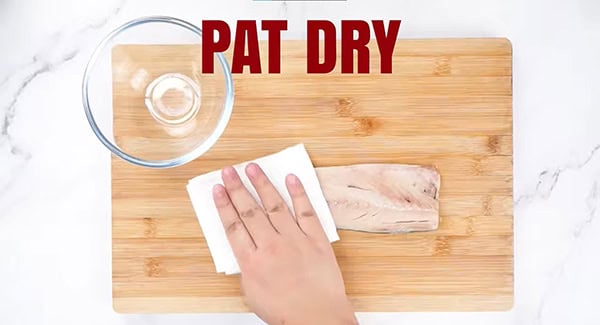 Mackerel being pat dry with a paper towel. 