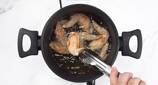 Chicken wings being deep fried until light brown. 