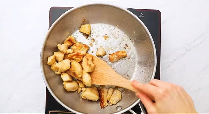 Chicken cubes in  a pan cooked to 70% doneness. 