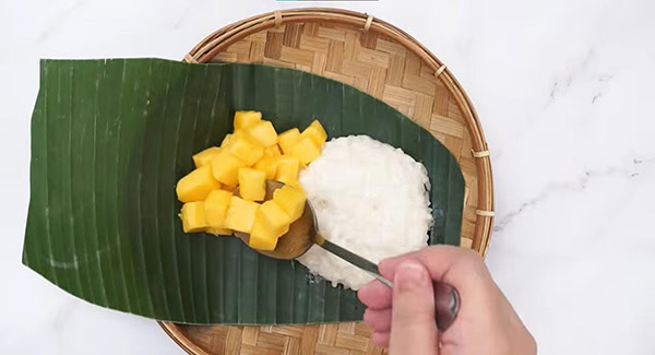 Mango sticky rice served on a banana leaf. 