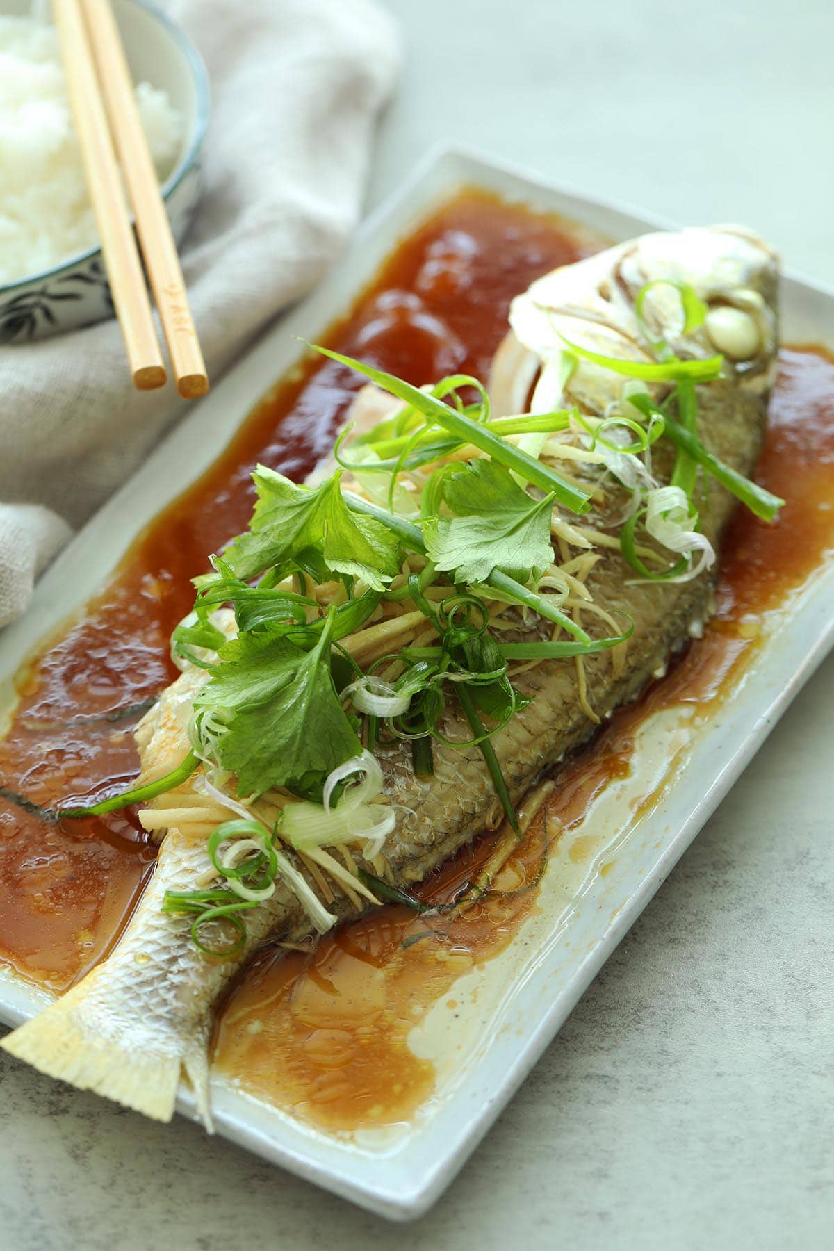 Steamed fish on a plate with soy sauce. 