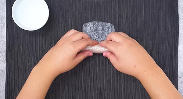 Rice paper with filling being folded into a cylinder. 