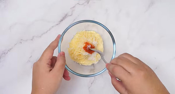 The remaining ingredients, except for the tobiko fish roes, are being mixed in a bowl using a spoon.