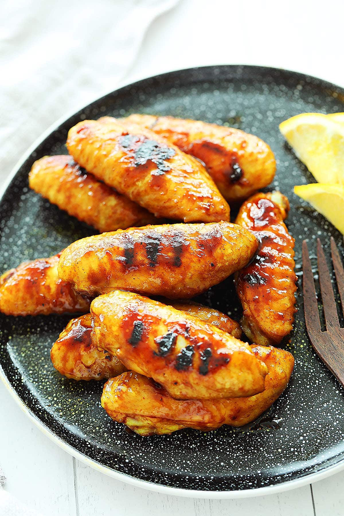 Honey wings served on a plate with lemon slices. 