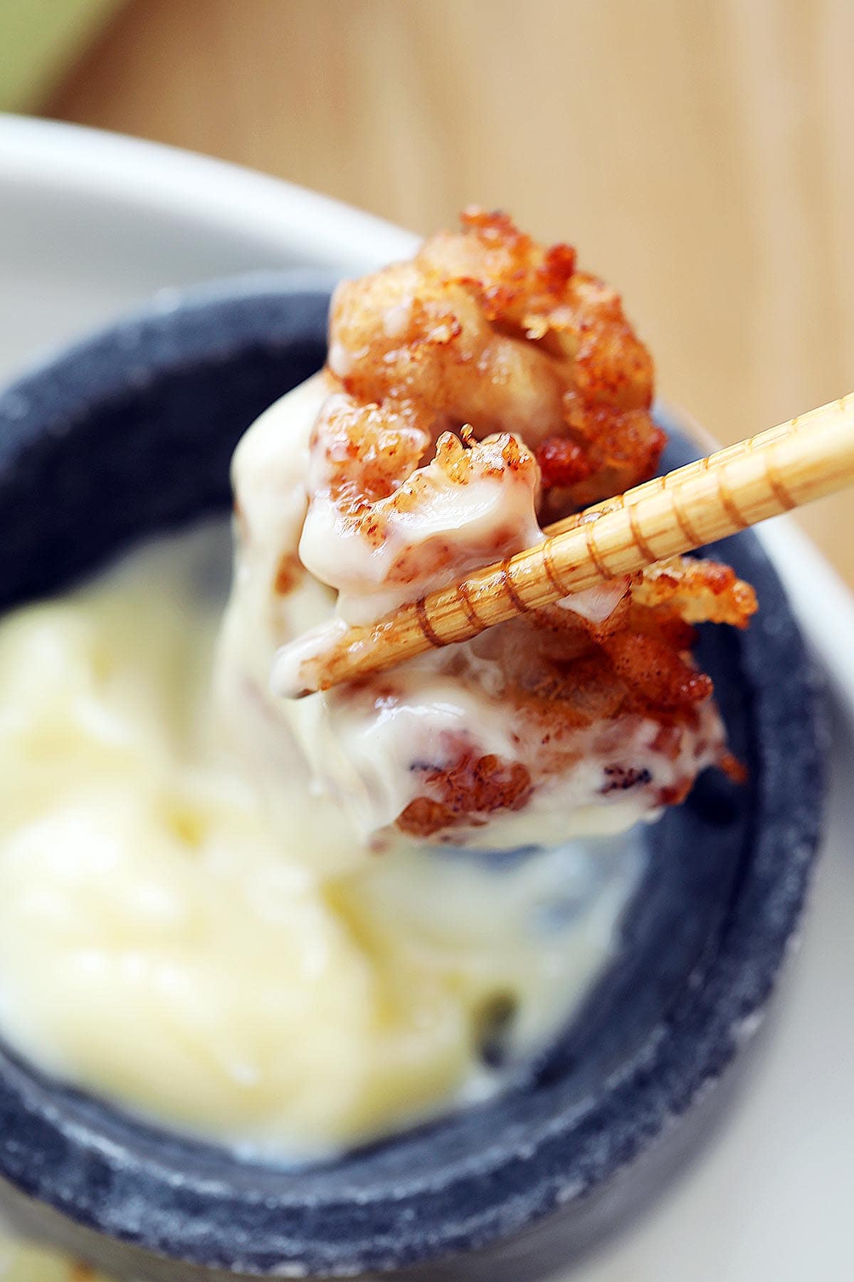 Dipping a piece of Japanese fried chicken with mayonnaise. 