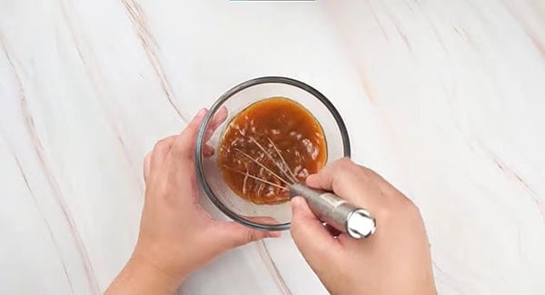 Sauce for shrimp and broccoli stir fry being mixed in a bowl using a whisk. 