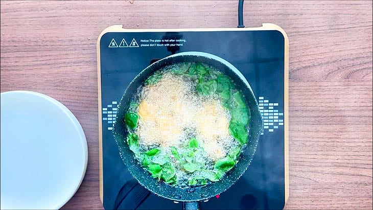 Chicken breast and Thai Basil Leaves frying in a pot of oil.