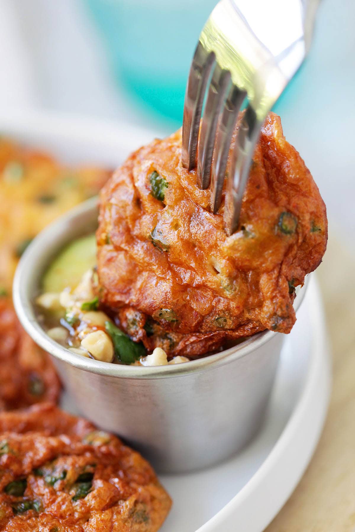 A piece of Thai fish cake dipped in dipping sauce. 