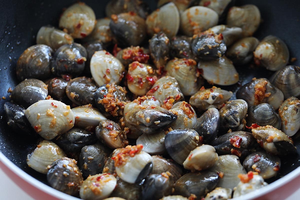 Stir fry spiced clams in a skillet. 