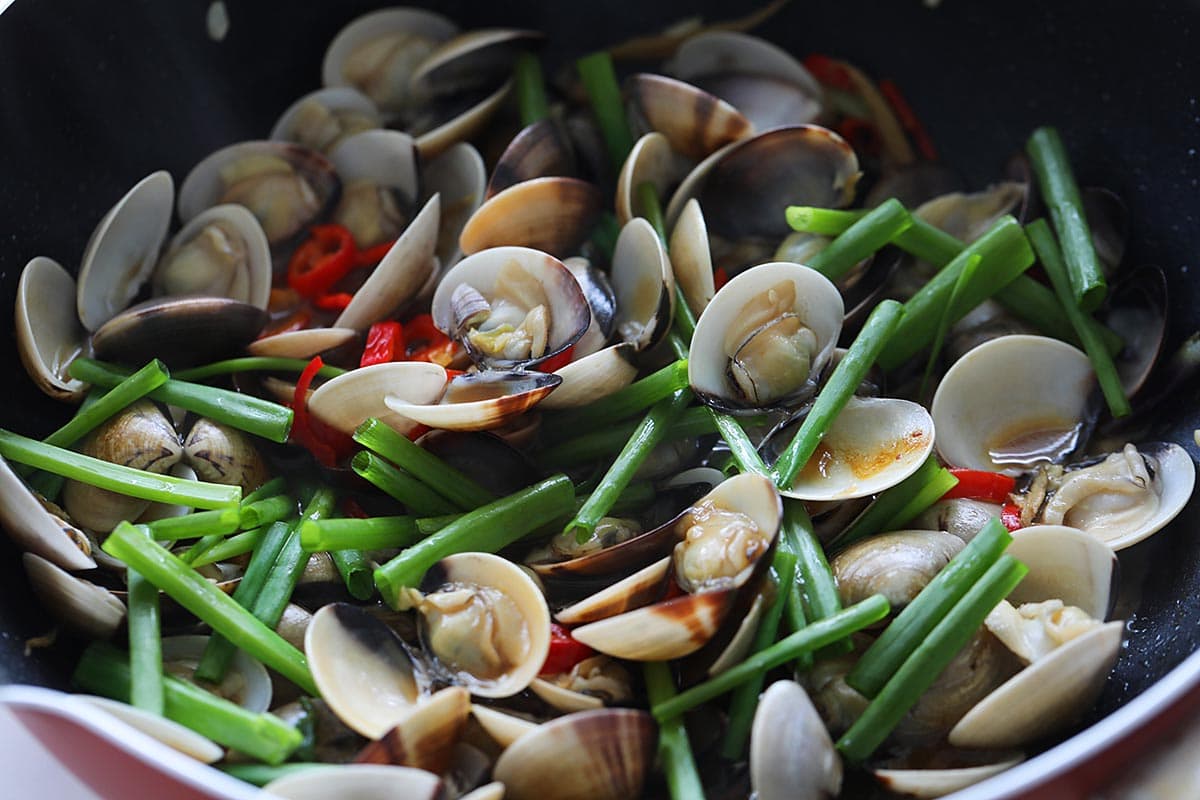 Adding chopped scallions to the clams. 