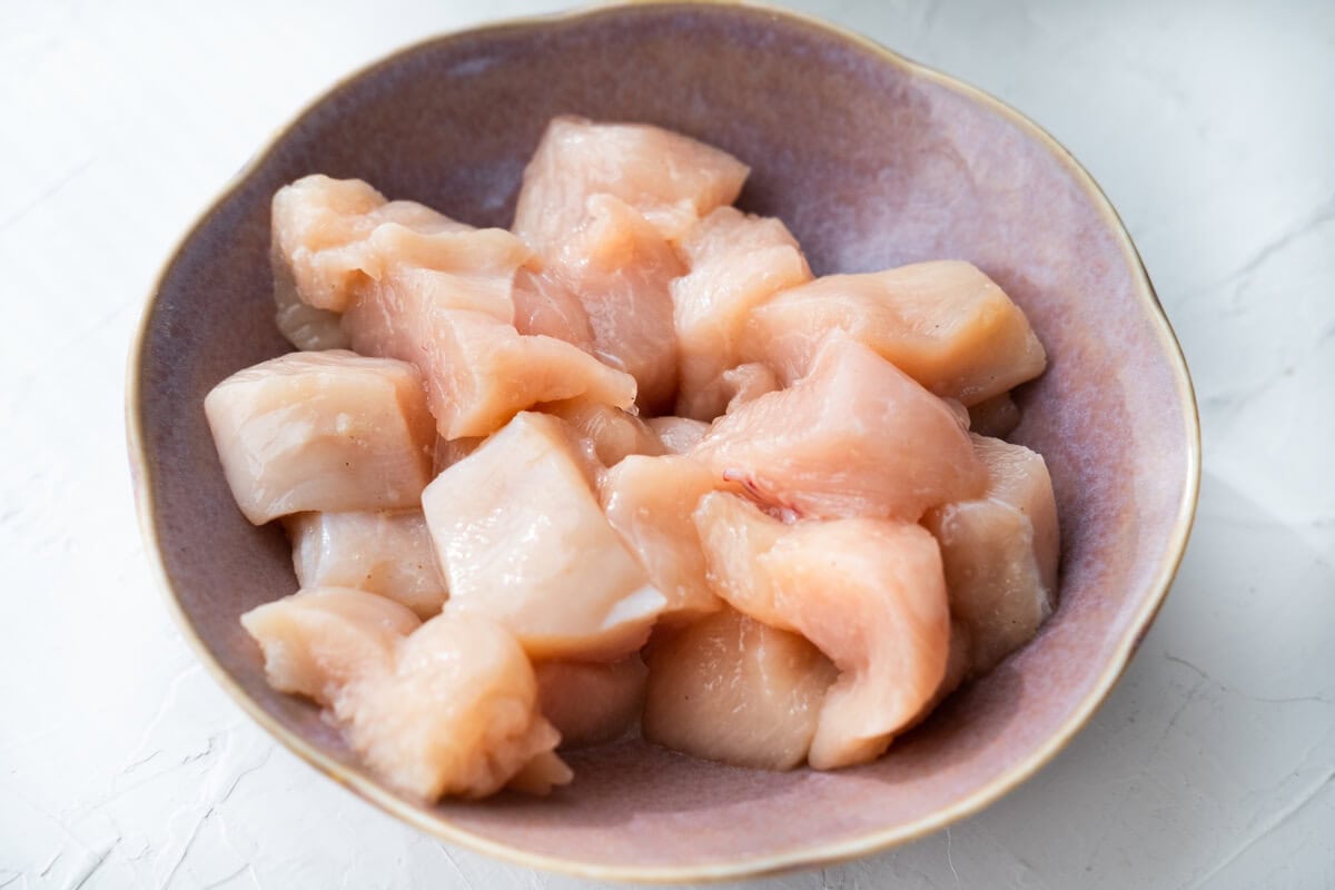 Marinating chicken cubes with the marinade in a bowl. 