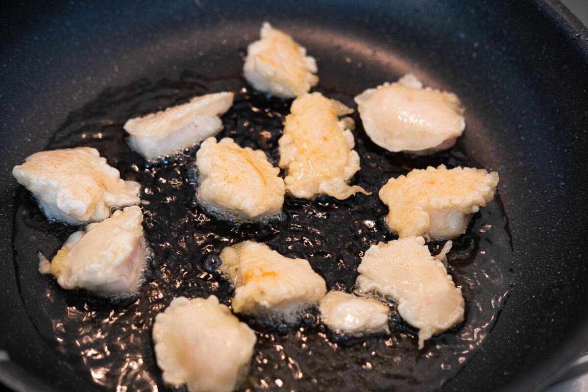 Battered chicken cubes in a frying pan. 