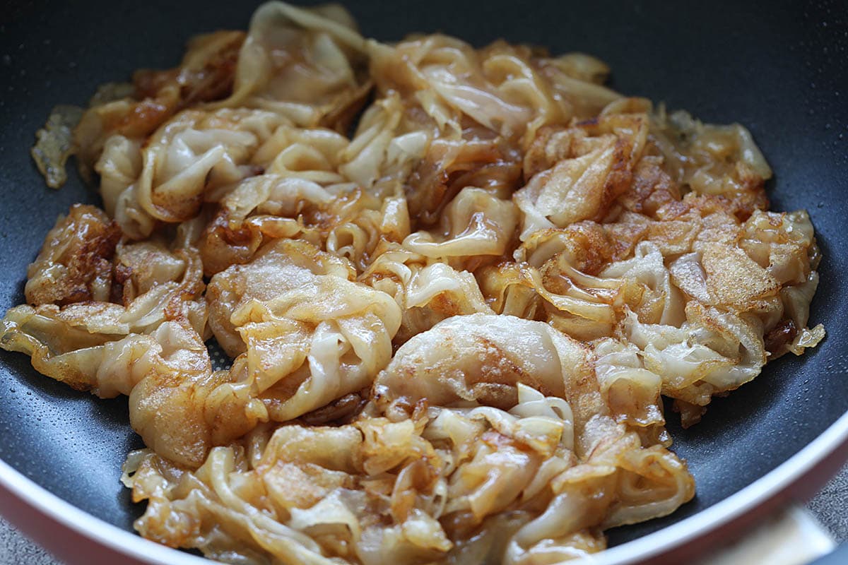 Flat rice noodles in wok.