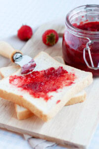 Strawberry jam in a jar with bread.