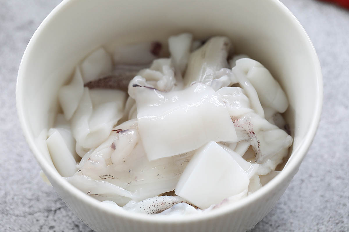 Cutting raw squid into bite-sized pieces.