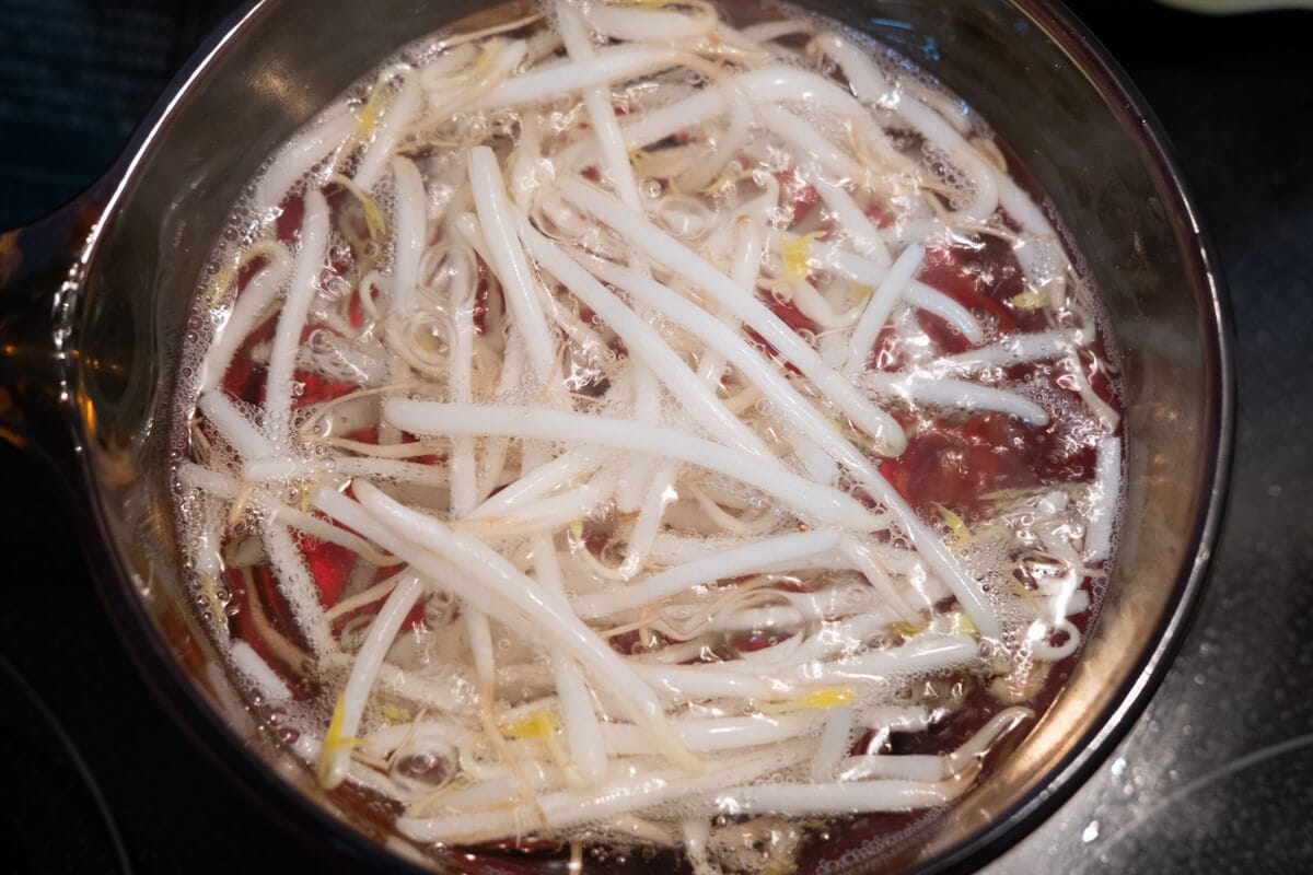 In a saucepan, blanch the bean sprouts in boiling water. 