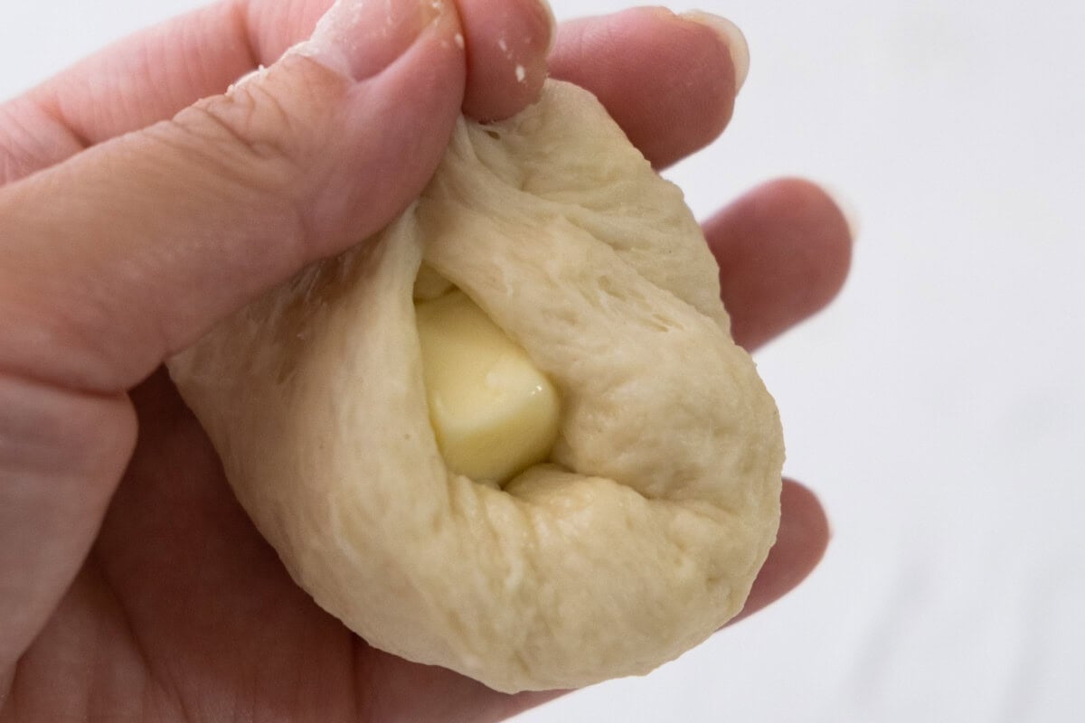 Place 1 teaspoon of butter in the center of a dough and pinch to seal it tightly. 