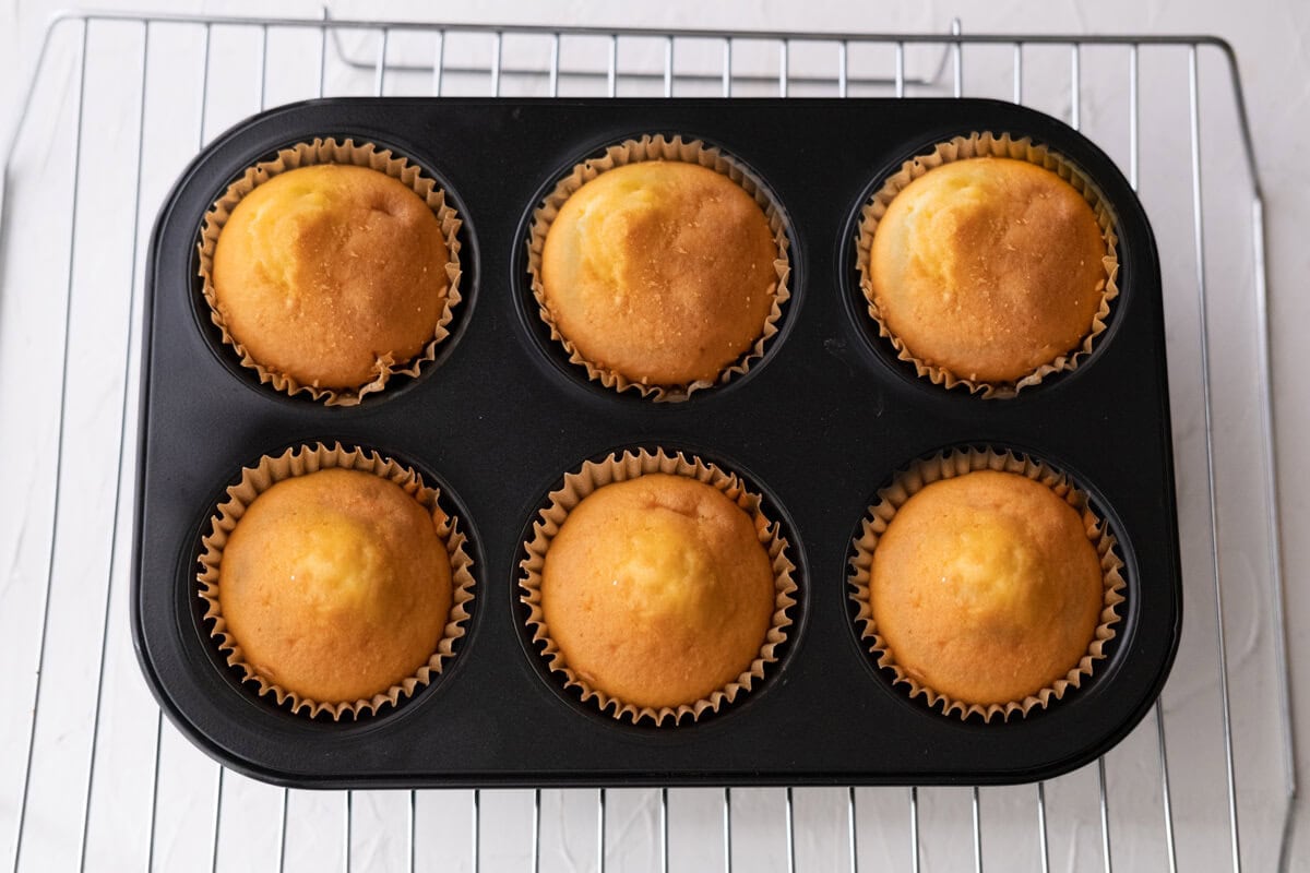 Golden mini egg cakes in a muffin tin.