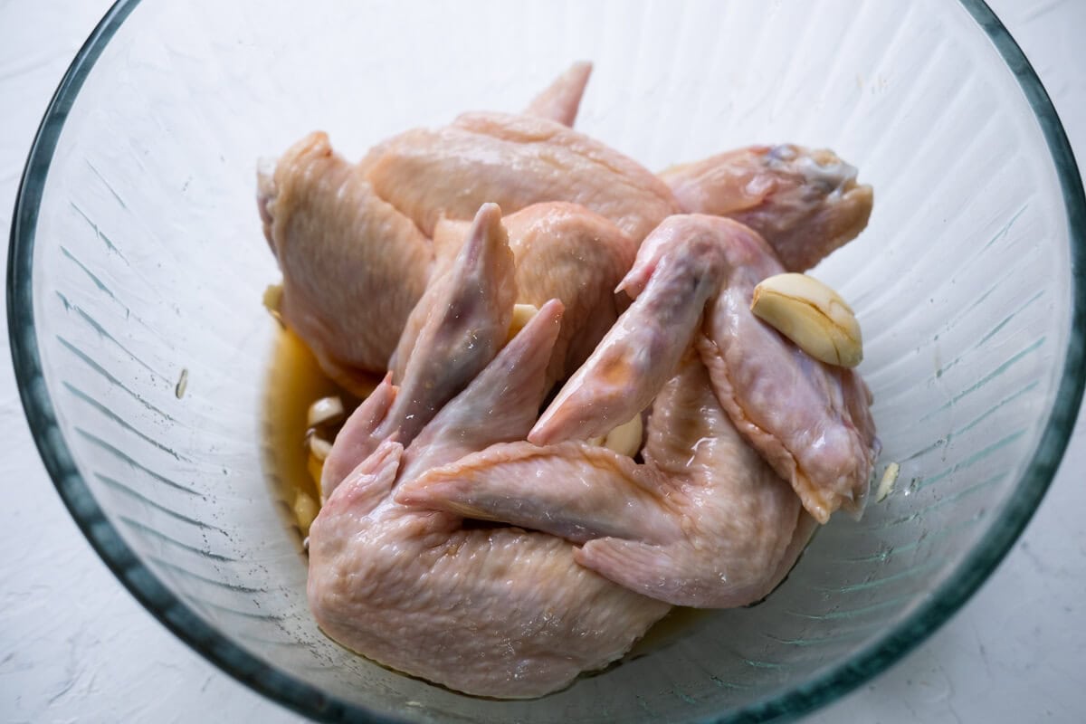 Marinate the chicken wings with fish sauce, sugar, and crushed garlic in a large bowl. 