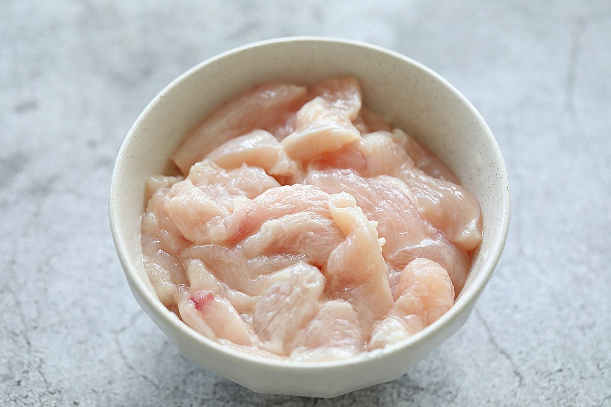 Chicken marinated with cornstarch in a bowl.