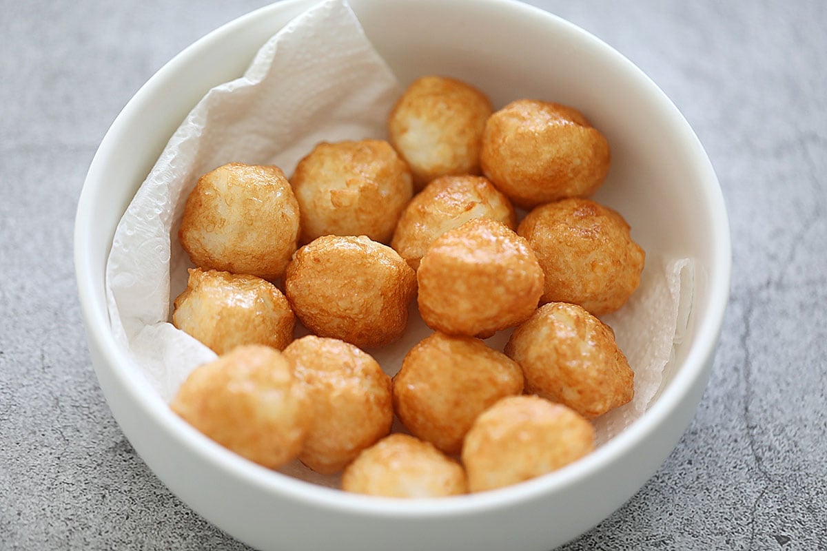 Fried cuttlefish balls in a bowl lined with paper towels.